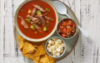 Sopa de tortillas con tiritas de cadera de cerdo, aguacate y queso