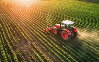 Tractor trabajando en un cultivo agrícola al atardecer