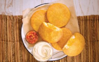 Arepas de huevo doradas con hogao y suero costeño